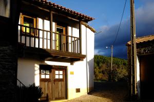a white house with a wooden door and a balcony at Casa da Mencha in Vinhais