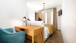 a bedroom with a bed with a desk and a blue chair at Veneziano Boutique Hotel in Heraklio