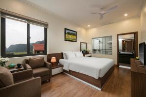 a bedroom with a bed and a couch and a tv at Tam Coc Holiday Hotel & Villa in Ninh Binh