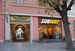 a store front of a pink building with a subway sign at Pensiunea Casa Helis in Sibiu