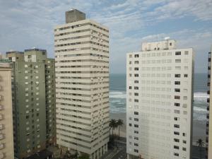 uitzicht op twee hoge gebouwen en de oceaan bij Quarto com café nas Pitangueiras in Guarujá