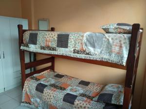 twee stapelbedden in een kamer met een dekbed erop bij Quarto com café nas Pitangueiras in Guarujá