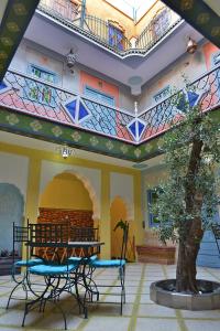 un bâtiment avec une table et des chaises dans une cour dans l'établissement Riad Aicha Marrakech, à Marrakech