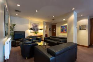 sala de estar con muebles de cuero negro y TV en Britannia Leeds Bradford Airport en Bramhope