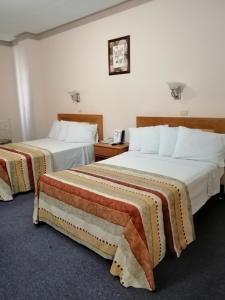 una camera d'albergo con due letti e un telefono di Hotel Astromundo a Reynosa
