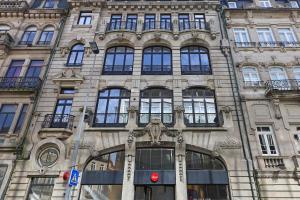 a tall building with a red traffic light in front of it at FLH Sá da Bandeira Luxury Apartment in Porto