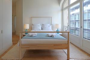 ein Schlafzimmer mit einem Bett und einem großen Fenster in der Unterkunft FLH Sá da Bandeira Luxury Apartment in Porto