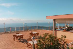 a patio with tables and chairs and the ocean at Ocean Gardens in Funchal