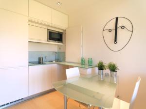kuchnia ze szklanym stołem i zegarem na ścianie w obiekcie FLH - Porto Charming Flat w mieście Matosinhos
