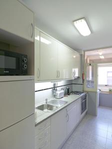 una cucina bianca con lavandino e forno a microonde di FLH Porto Comfort Flat a Porto