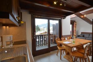 a kitchen and dining room with a table and a balcony at VVF Résidence Megève Mont-Blanc in Megève