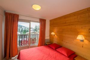 a bedroom with a red bed and a window at VVF Résidence Megève Mont-Blanc in Megève