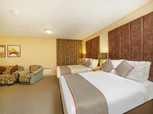 a hotel room with two beds and a couch at OYO Flagship Brentwood in Aberdeen
