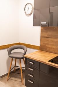 einen Stuhl in einer Küche mit einer Uhr an der Wand in der Unterkunft Rezidence Hadovitá in Prag