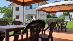 un patio al aire libre con mesas, sillas y sombrillas en La Casa delle Rondini, en Lamporecchio