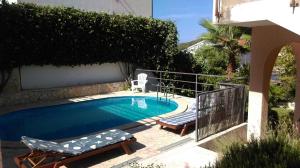 a swimming pool with two lounge chairs next to it at Apartmani Zulin in Seget Vranjica
