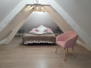 a bedroom with a bed and a pink chair at Gîte YZEN près de Honfleur in Conteville