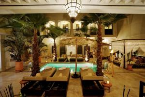 uma sala de estar com piscina e palmeiras em Riad Saranda Hotel Restaurant & Spa em Marrakech