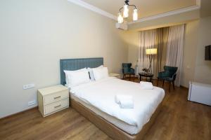a bedroom with a large white bed and chairs at A Hotel Yerevan in Yerevan