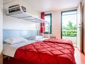a bedroom with a bed with a red blanket at Première Classe Lille Sud Henin Beaumont in Noyelles-Godault