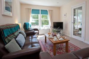a living room with a leather couch and a coffee table at Killinallan Cottage in Port Charlotte