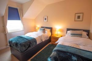 a bedroom with two beds and a window at Killinallan Cottage in Port Charlotte