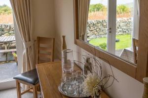 a table with glasses on it with a window at Killinallan Cottage in Port Charlotte