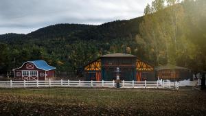 a building with a white fence in front of a mountain at Vasilikia Mountain Farm & Retreat in Pávliani