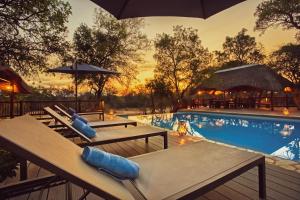 una piscina con tavoli e ombrelloni accanto al resort di Vuyani River Lodge a Hoedspruit