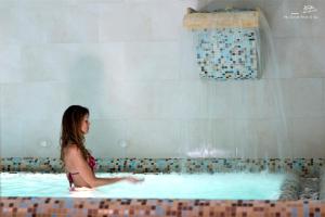 a woman is sitting in a swimming pool at Hotel Villa Durrueli Resort & Spa in Ischia
