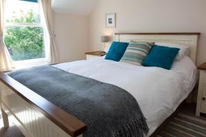 Un dormitorio con una cama blanca con almohadas azules y una ventana en Sanaigmore Cottage en Port Charlotte
