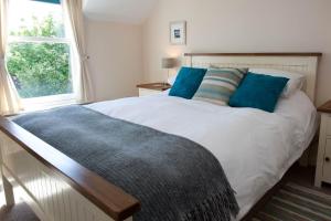 una camera da letto con un letto bianco con cuscini blu e una finestra di Sanaigmore Cottage a Port Charlotte