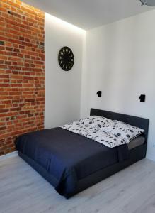 a bed in a room with a brick wall and a clock at Charming Apartment in The City Centre, Łódź in Łódź
