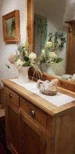 a wooden dresser with a mirror and flowers on it at Albergo GARNI' AURORA in Tret