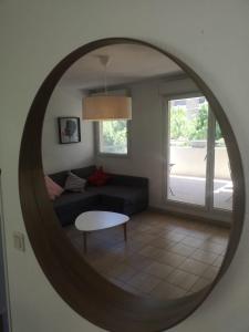 een woonkamer met een bank en een ronde spiegel bij Charmant F2 Port Marianne (15 Min Plages/Centre-ville) in Montpellier