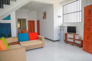 a living room with a couch and a tv at Blue Berry Villa in Hikkaduwa