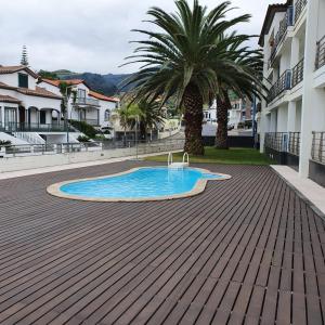 a swimming pool in a courtyard with a palm tree at Black'nYellow Place in Vila Franca do Campo