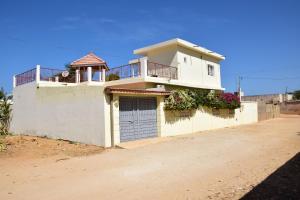 a white house with a gate and a balcony at Villa & Appartement Du Soleil Ngaparou in Ngaparou