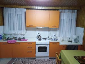 una cocina con armarios naranjas y un horno de fogón blanco en Ioannina Traditional House en Ioánina