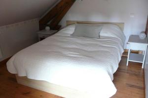 ein großes weißes Bett in einem Schlafzimmer mit Holzboden in der Unterkunft Gite du hérisson in Saulieu