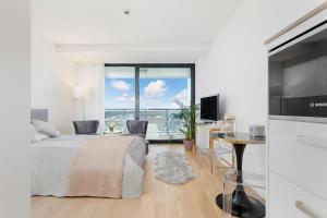 a white bedroom with a bed and a balcony at Seaside Park Private Aurora 502 in Kołobrzeg