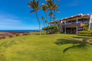 einen Außenblick auf ein Haus mit Palmen und dem Meer in der Unterkunft Mauna Lani Point in Waikoloa
