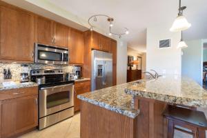 a kitchen with stainless steel appliances and wood cabinets at Kaanapali Alii, a Destination by Hyatt Residence in Lahaina