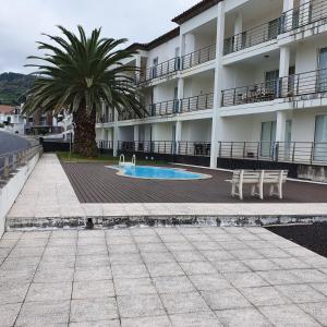 a building with a palm tree and a swimming pool at Black'nYellow Place in Vila Franca do Campo