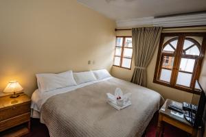 Un dormitorio con una cama con una vela. en Hostal El Peregrino, en Cusco