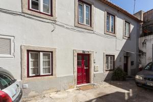 a white house with a red door on a street at LxFactory Apartment in Lisbon