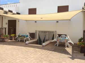 - un patio avec des chaises et un auvent dans un bâtiment dans l'établissement Appartamenti STELLA MARINA- Posto Rosso, à Alliste