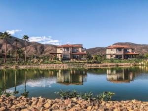 a couple of houses sitting on top of a lake at El Cielo Resort in Valle de Guadalupe