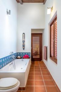 ein Bad mit einer Badewanne und einem WC in der Unterkunft Pelican Villa in Lagun