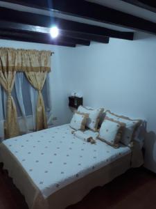 Schlafzimmer mit einem Bett mit weißer Bettwäsche und Kissen in der Unterkunft ALMANIK in Villa de Leyva